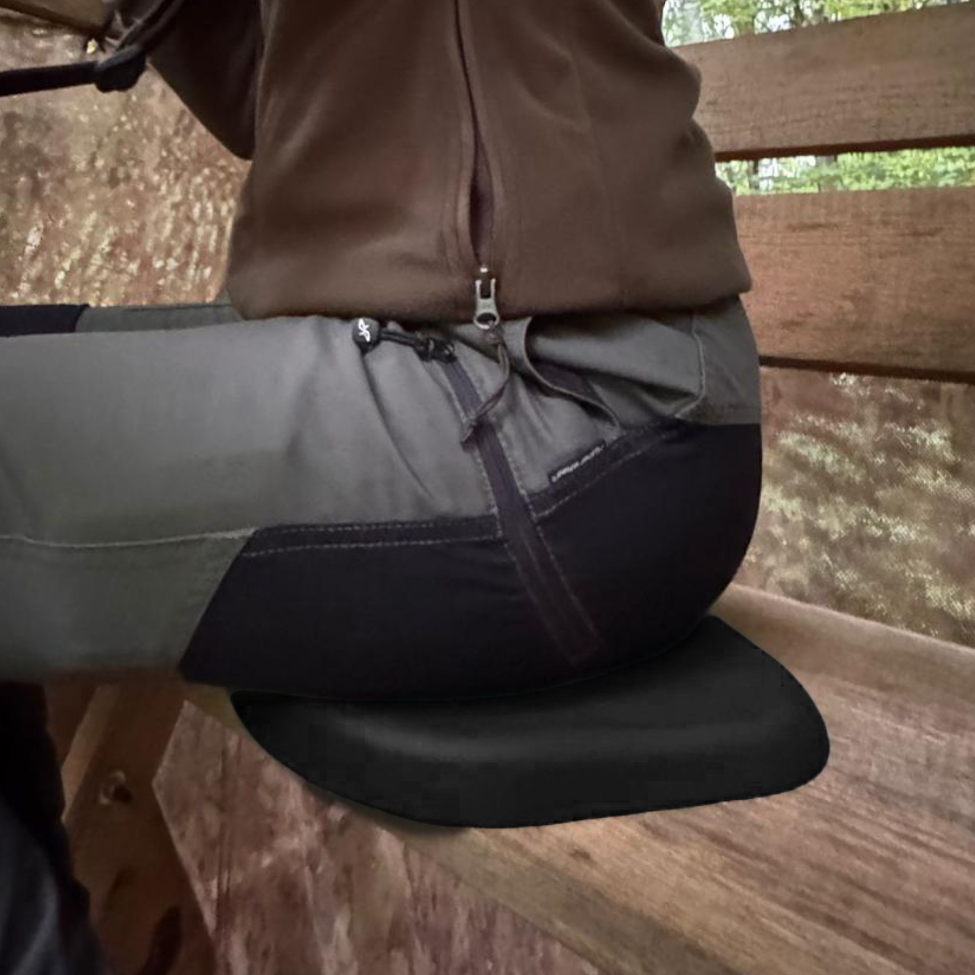 Person in Arbeitshose sitzt auf dem Sitzkissen auf einer Holzbank