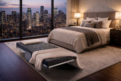 Beistellbett Relax + Move in schwarz mit hellem Überwurf in Hotelzimmer bei Nacht.